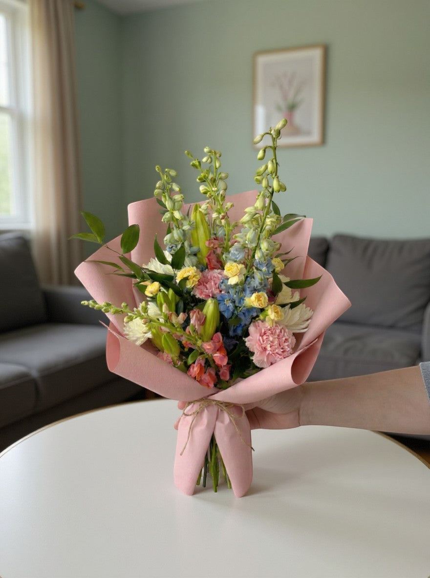 Lakewood Florist Morning Dew Bouquet: pastel pink, white, lavender, and yellow spring flowers with green foliage.