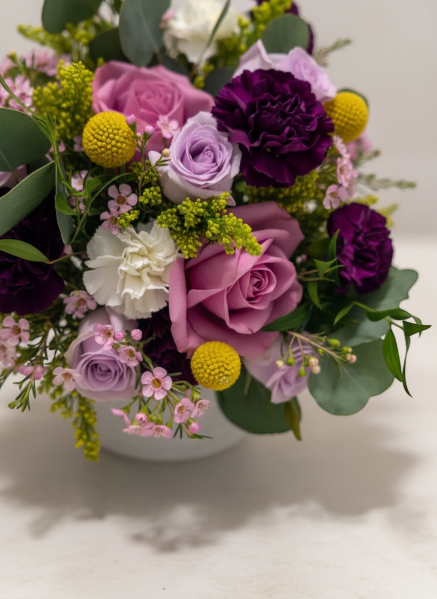 Lakewood Florist Violet Story Bouquet: A vibrant mix of purple roses, carnations, and delicate pink and yellow accents with lush greenery.